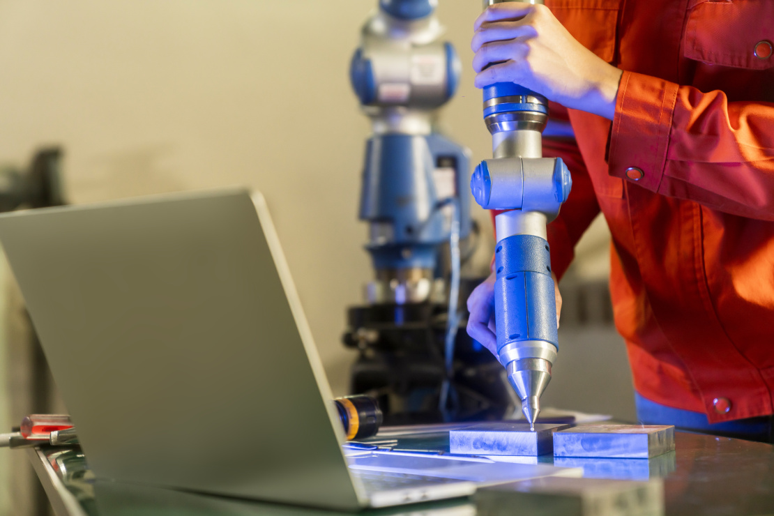 asian_female_engineer_specialist_with_measuring_machine_with_manipulator_armthreedimensional_coordinate_measurement_check_sizes_3d_check_sizes_parts_cmm_after_machining_process.jpg